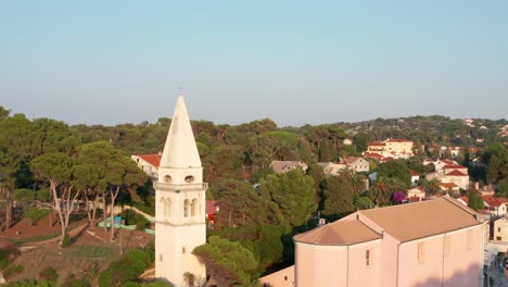 mid-height aerial shot circling around a church tower in veli losinj, croatia