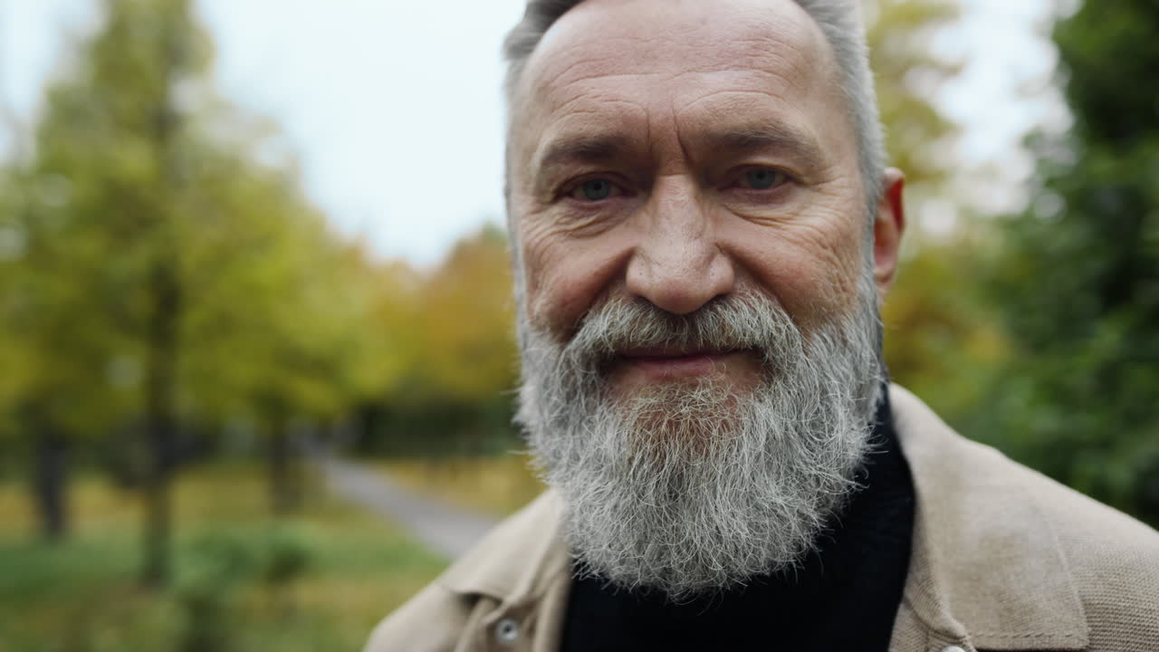 retrato de un hombre barbudo sonriente en la calle. un caballero positivo en el parque.