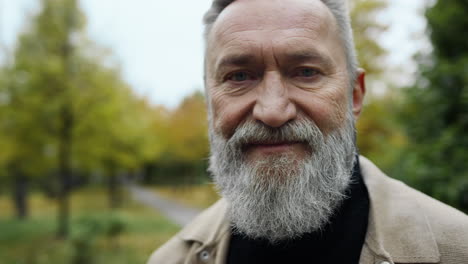 portrait of smiling bearded man in street. positive gentleman staying in park.