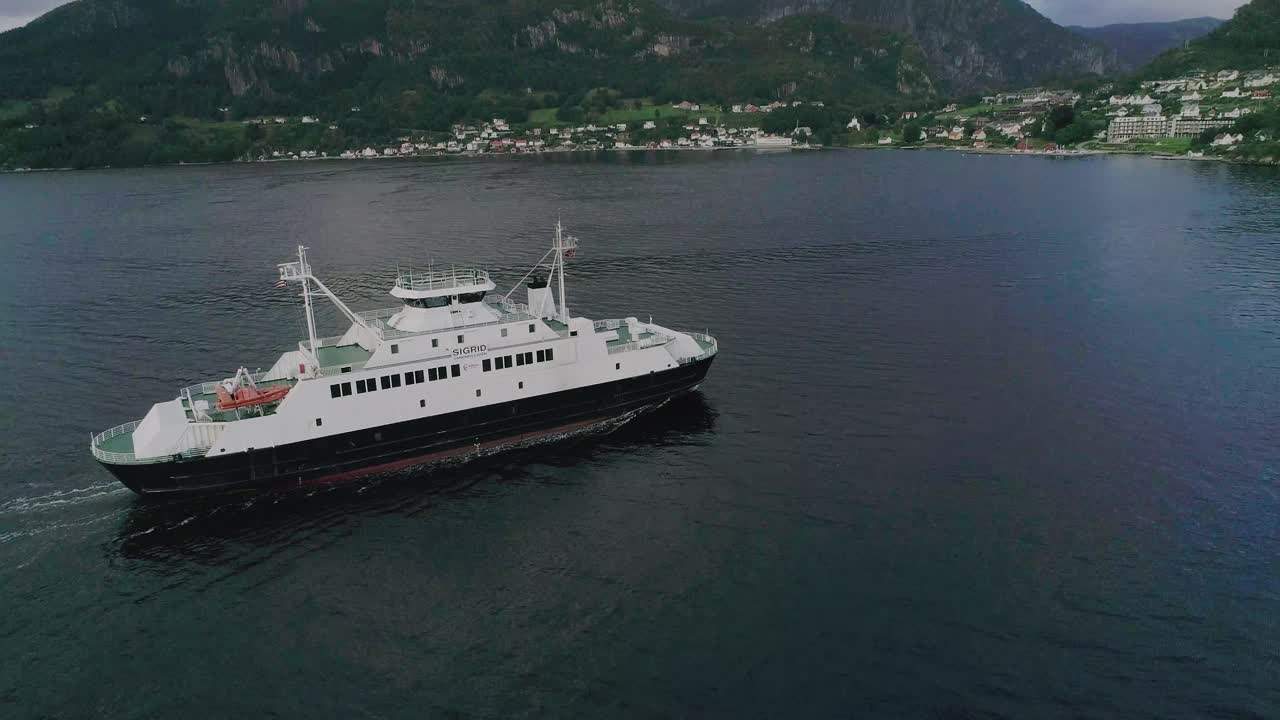 panorámica aérea en cámara lenta alrededor de un ferry noruego que entra en un pequeño pueblo