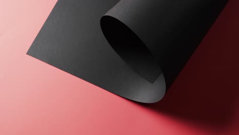 Close-up-of-roll-of-black-paper-and-copy-space-on-red-background