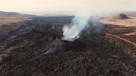 volcanic wasteland with active smoking volcano eruption, iceland