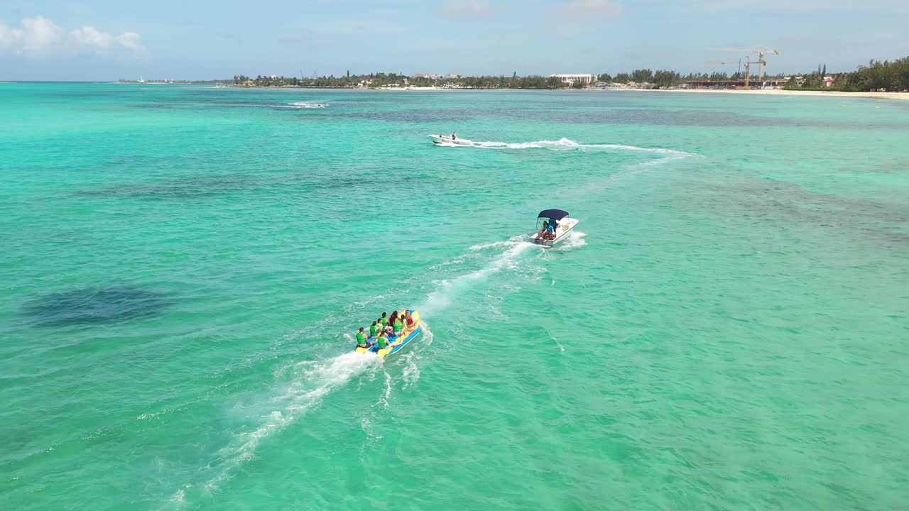 Summer Fun in Nassau Bahamas. Aerial View of People on Tow Tube and Towing Boat in Tropical Sea