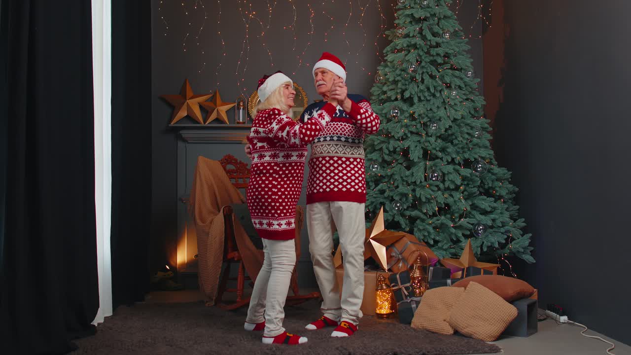 alegre y sonriente pareja de abuelos casados en una habitación decorada celebrando la navidad juntos
