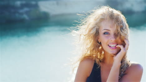 Young-Woman-Smiling-Into-The-Camera-Playing-With-Her-Beautiful-Hair-On-The-Beach-Portrait