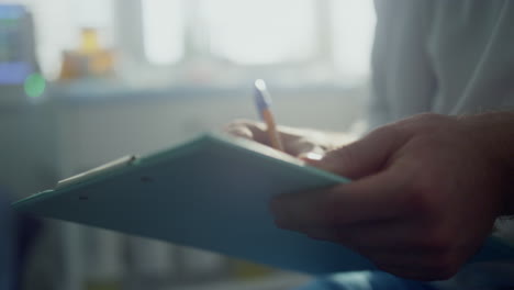 Doctor-hands-filling-patient-registration-form-close-up.-Physician-making-notes.