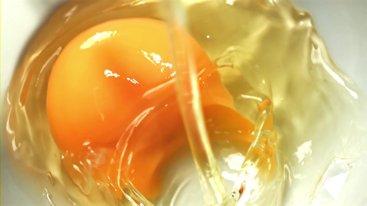 Close-Up of a Fresh Egg Yolk and White Pouring into a Bowl