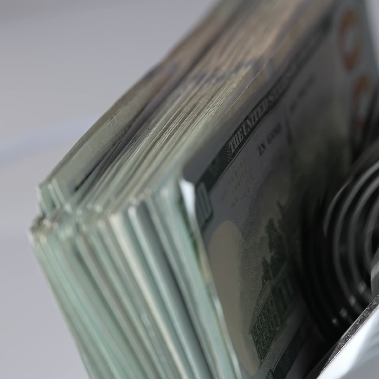 Quickly counted one hundred dollar bills in money counting machine. Rotating mechanism of equipment close up. Blurred backdrop