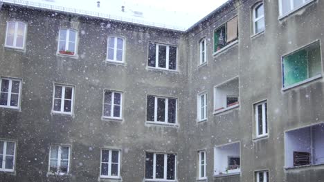 slow motion of snowflakes falling down in front of grey old building