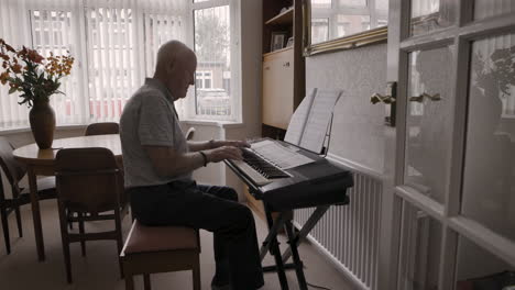 senior man playing piano at home