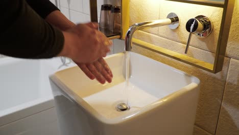 man washing hands with water and soap in bathroom