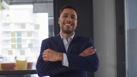 portrait of mixed race businessman with arms crossed smiling looking at camera