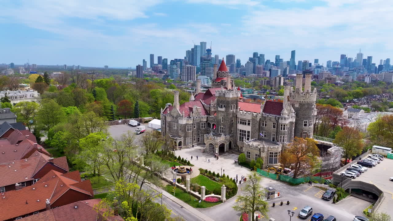 Slow aerial drone shot around Casa Loma with CN Tower and Toronto cityscape in the background
