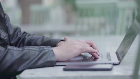 young man using his laptop and typing on it medium camera shot