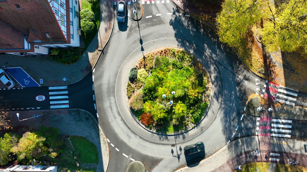 Drone footage showing detailed top-down view of city roundabout with trees and moving cars in Sopot, Poland