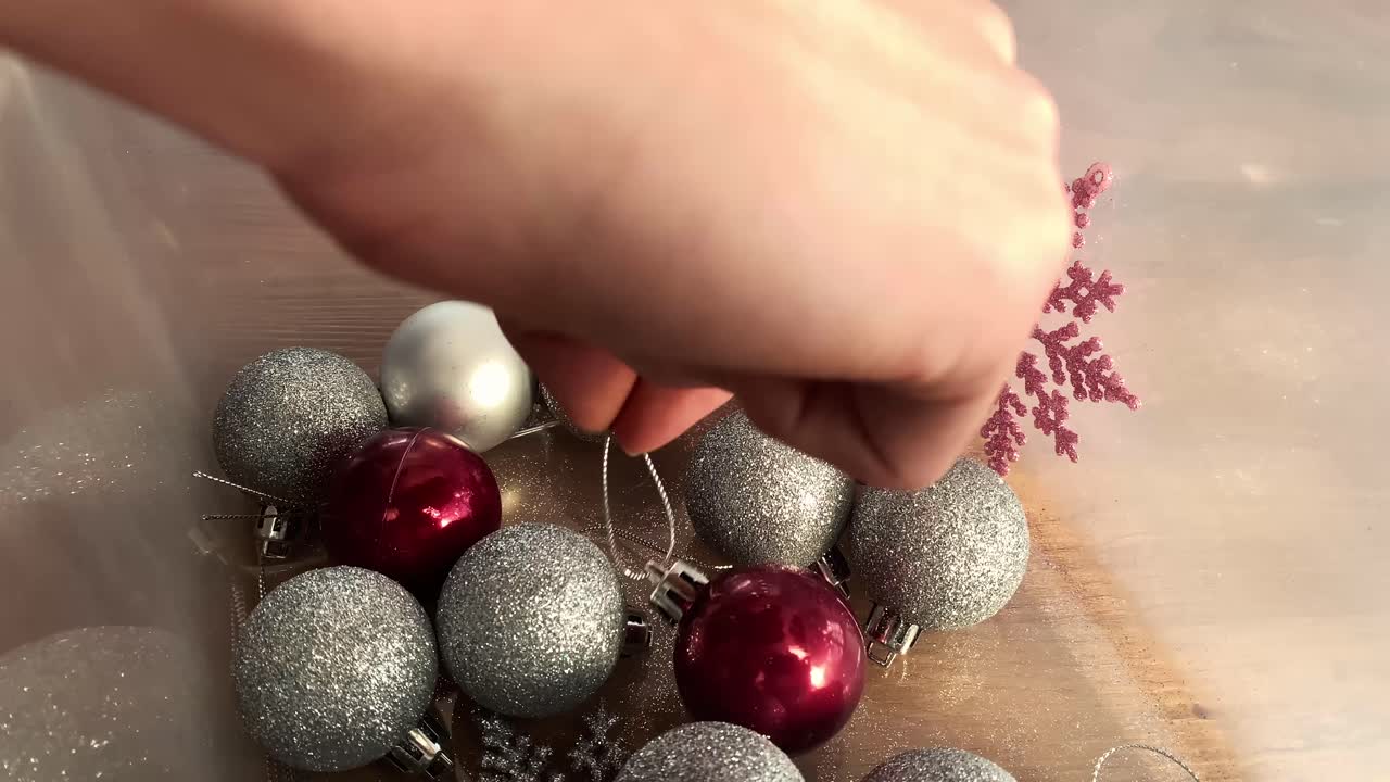 mujer recogiendo una bombilla roja de árbol de navidad de una caja de plástico transparente