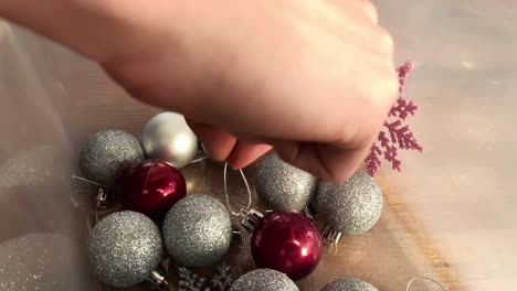 woman picking red christmas tree bulb from a transparent plastic box