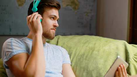 man listening music on digital tablet at home 4k