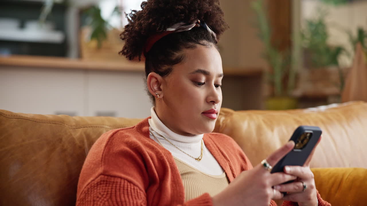 Woman Sitting on a Couch Smiling and Using Her Phone