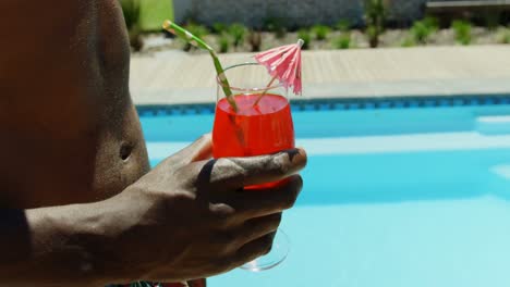 Mid-section-of-man-holding-cocktail-drink-near-swimming-pool-4k