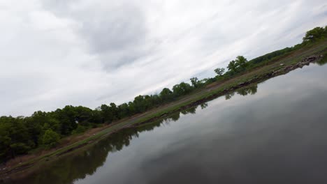 Eine-FPV-Drohnenansicht-Aus-Geringer-Höhe-über-Einem-See-Mit-Reflektierender-Oberfläche