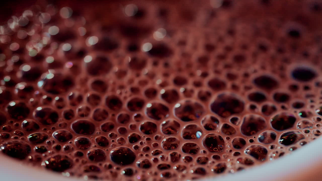 Top down close up of a warm cup of hot chocolate covered in foamy bubbles