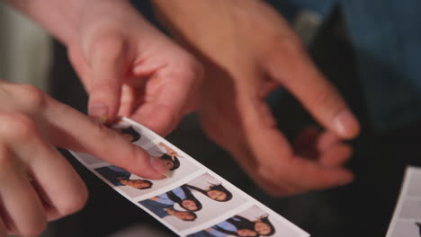 close up of a group of friends having fun looking at prints from photo booth 1