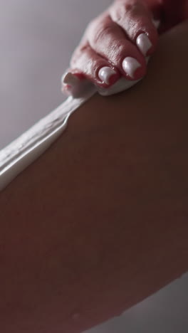 woman applies shaving foam on leg in bathroom closeup. lady uses cosmetic product for skin before hair removal in shower. skincare and beauty