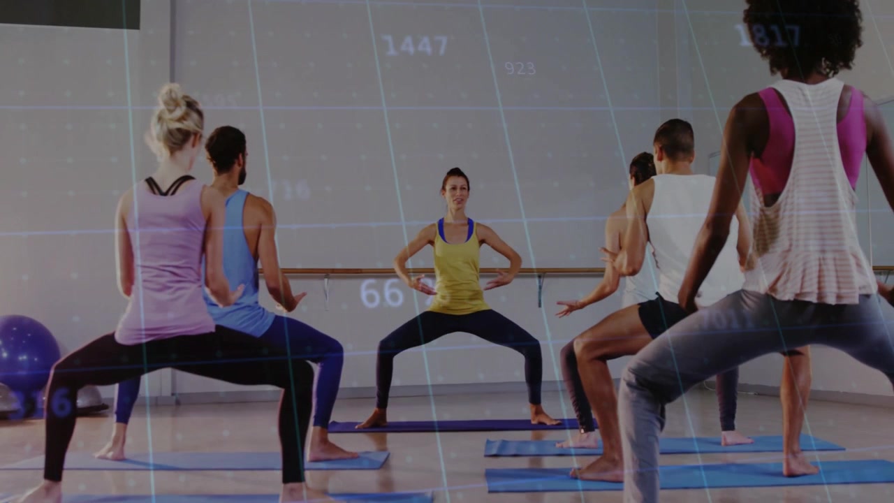 Instructor cueing class stepping into plié squat in fitness studio on blue mats with digital grid