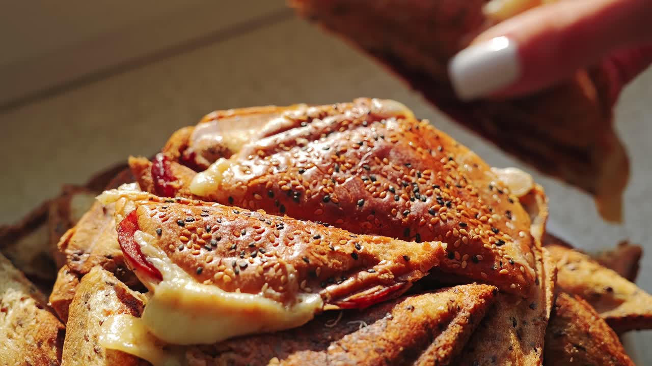Close up slow motion reveals hand gently placing toast on stacked sandwiches