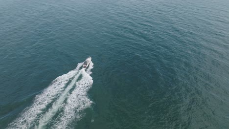 speedboat sailing in ocean leaving white wake - aerial drone shot