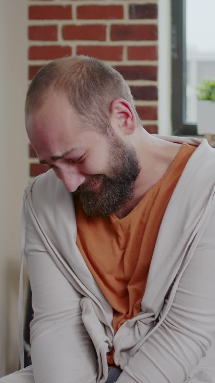 A man expressing sadness and crying indoors