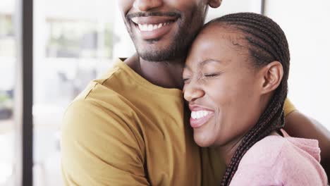 Happy-african-american-couple-smiling-and-embracing-in-living-room,-in-slow-motion