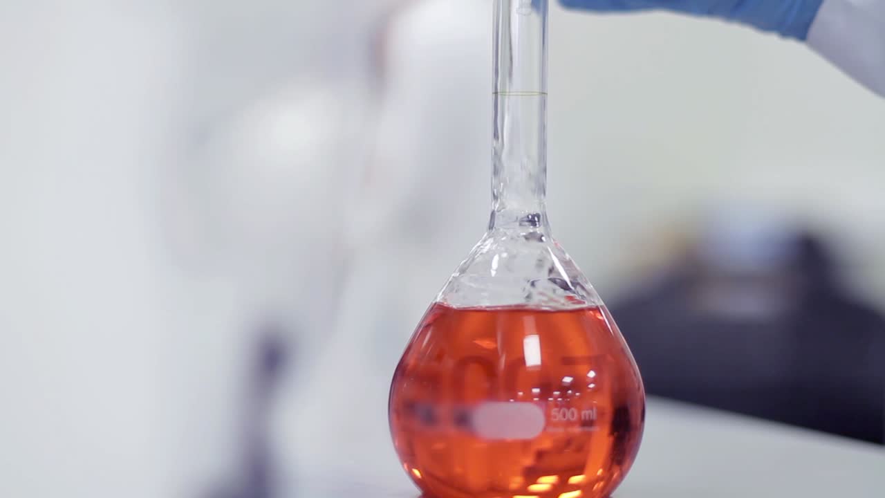 Scientist Pours Clear Liquid into Volumetric Flask in Laboratory