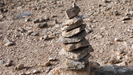 closeup of conical stone cairn to a reveal of the barren landscape behind