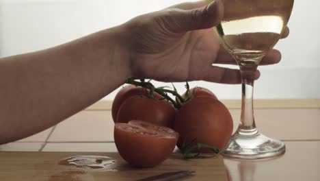 hand holding glass of white wine snacking on fresh vine tomatoes