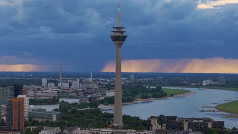 rhine tower dusseldorf with storm clouds on horizon, telephoto drone shot