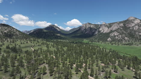 rocky mountains colorado usa on sunny summer day, flying above conifers and countryside road, drone shot