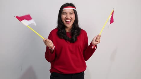 Cheerful young Indonesian female standing holding red white flag to celebrates Indonesia independence day