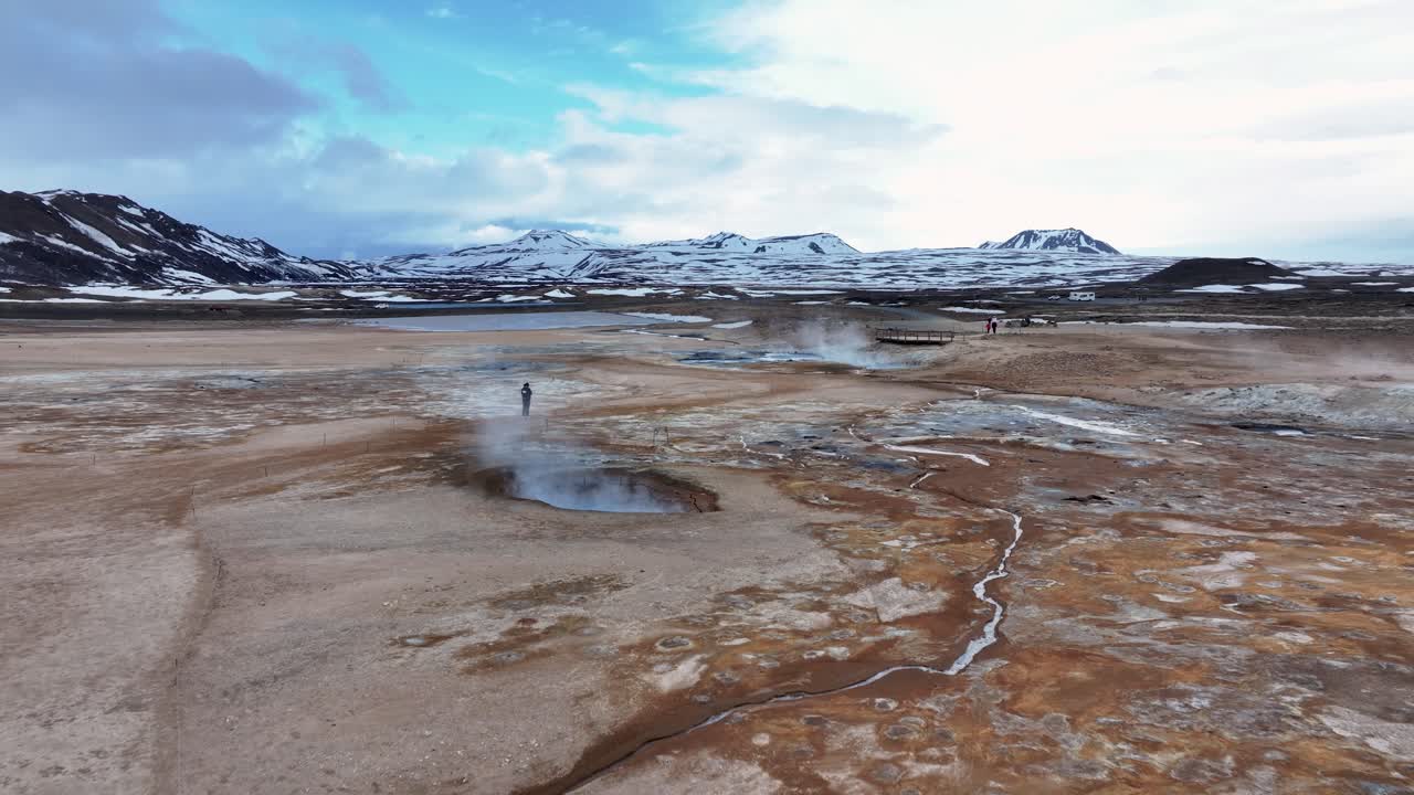 Behold the majestic sight of sulfuric smoker landscape near Myvatn at Reykjahlid in Iceland, with billowing smoke and a majestic mountain range in the background.