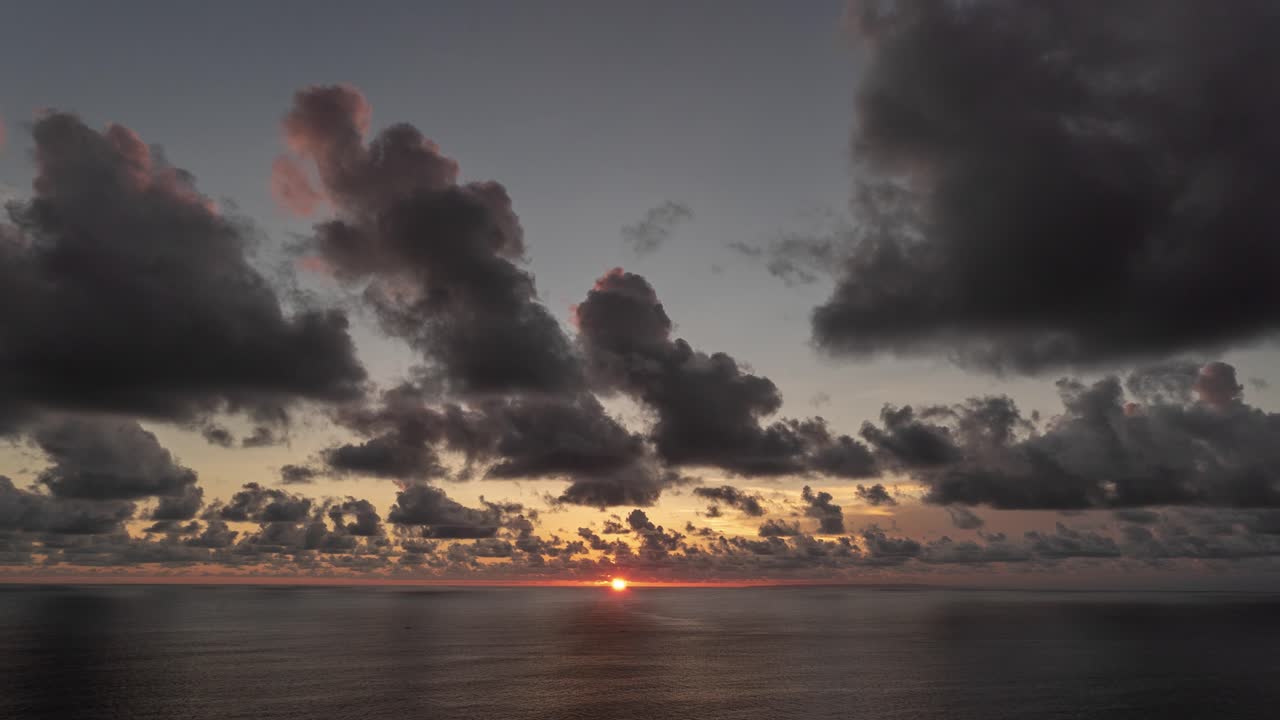 극적인 구름과 함께 바다 위에 해가 지는 것