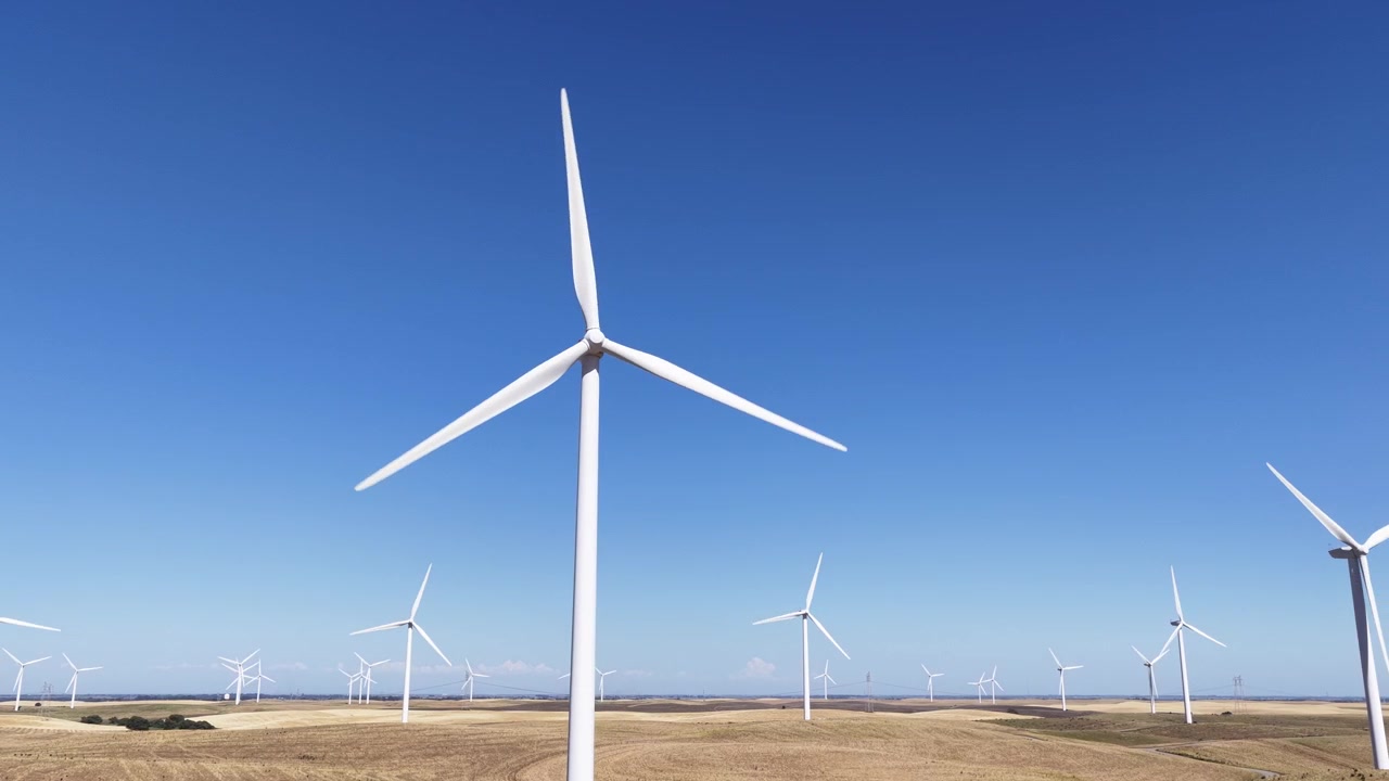 Vaste parc éolien avec des turbines en rotation sous un ciel bleu clair dans la campagne californienne. Des éoliennes modernes génèrent de l'électricité propre, verte et durable à partir de l'énergie éolienne par une journée ensoleillée.
