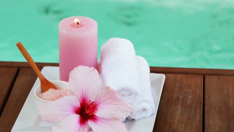 toallas, velas y flores rosas junto a la piscina.