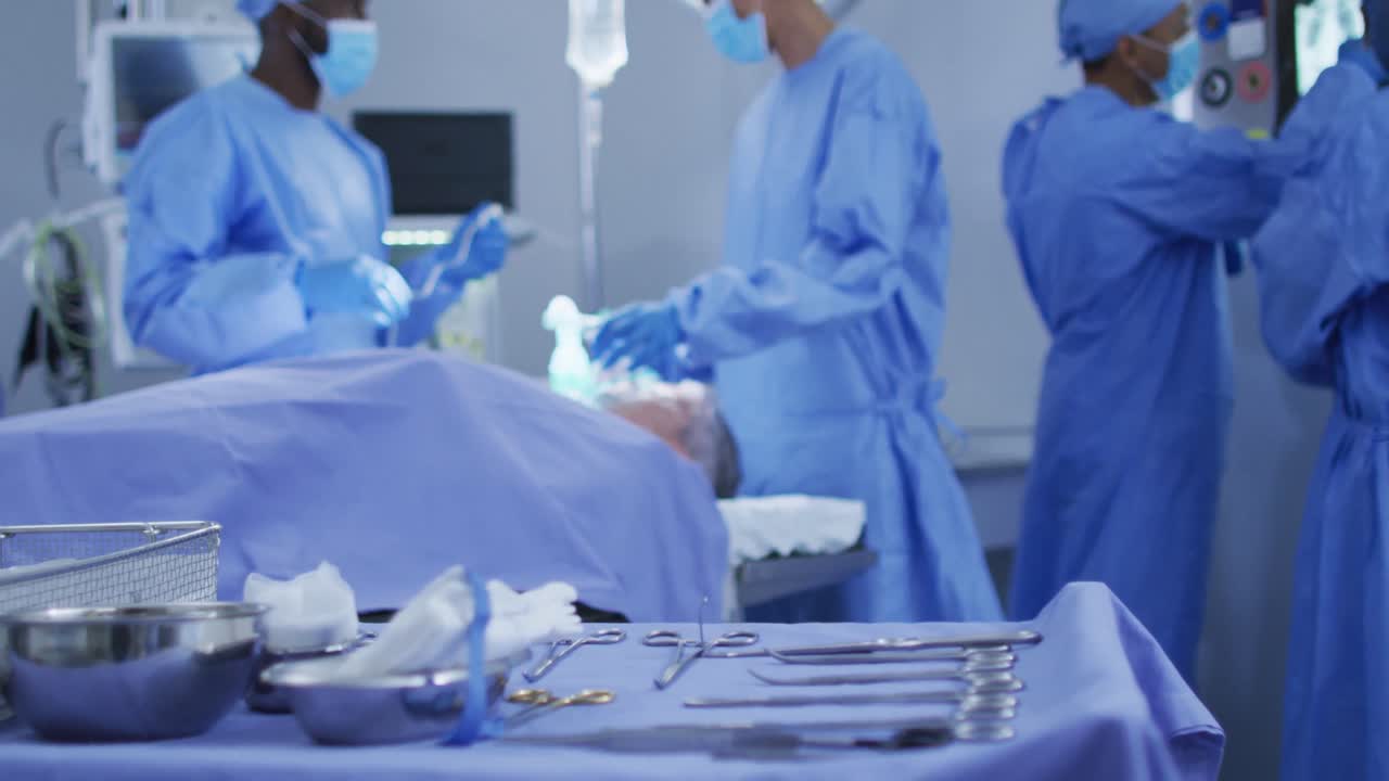 Mixed race surgeons wearing protective clothing putting patient to sleep in operating theatre