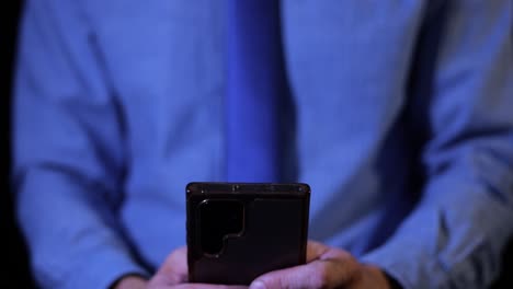 businessman working late at night on mobile phone, typing email to colleagues