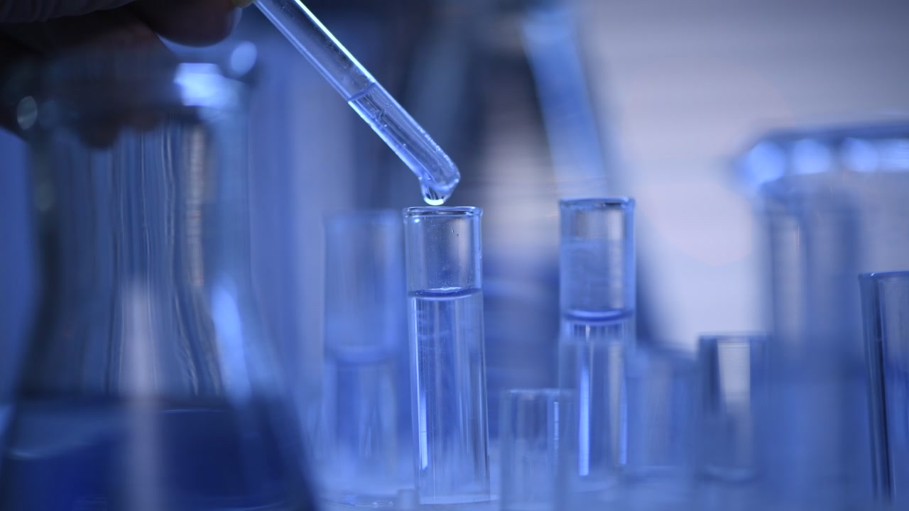 Scientist Pipetting Blue Liquid into a Test Tube in a Laboratory