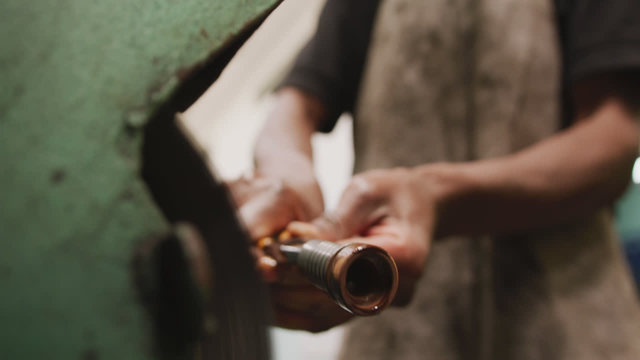 trabajador de fábrica afroamericano en una fábrica de pie en un banco de trabajo y trabajando en un metal