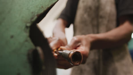 African-American-male-factory-worker-at-a-factory-standing-at-a-workbench-and-working-on-a-metal