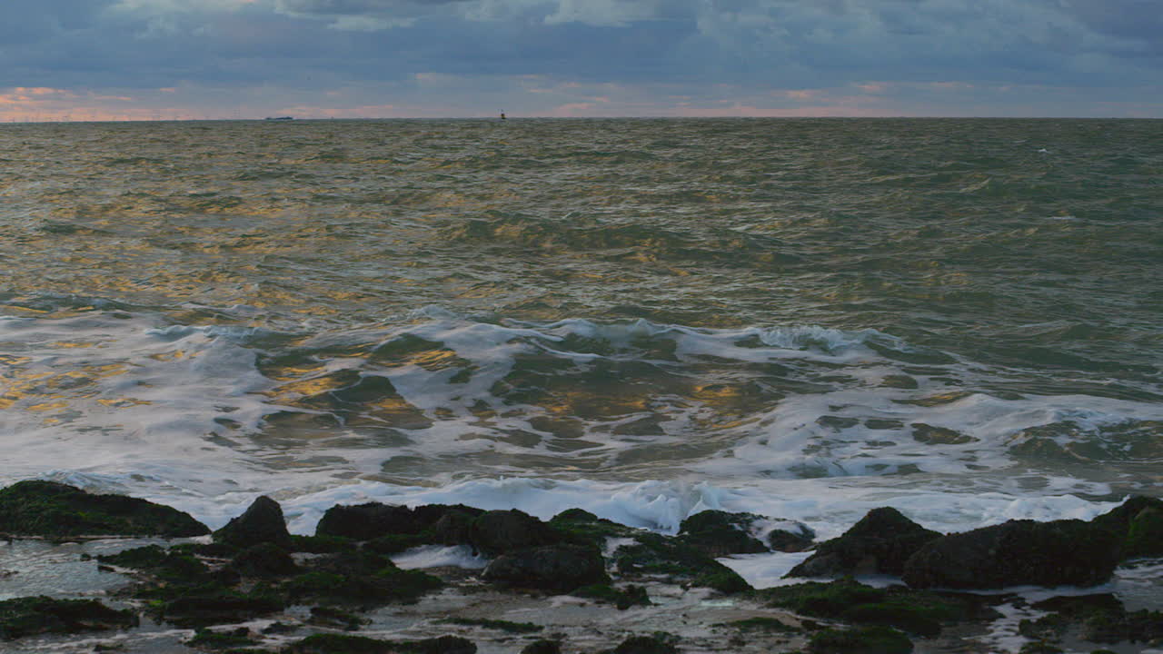 일몰 때 제방을 치는 북해의 파도