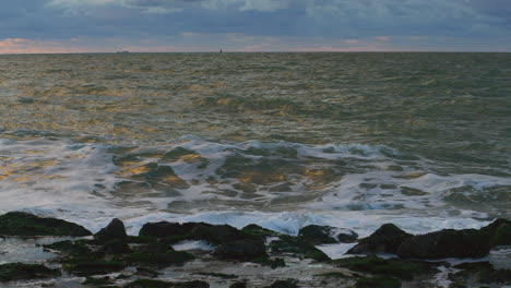 olas del mar del norte golpeando un dique al atardecer